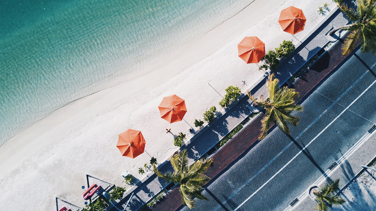 Top view of a beach with four orange umbrella