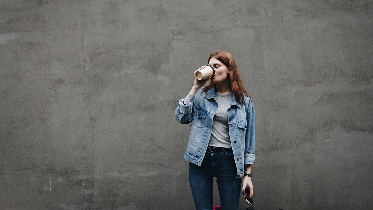 A girl drinking coffee with a gray background