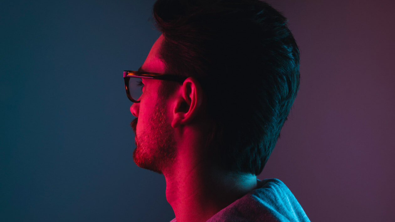 A boy wearing spectacles in red and blue light